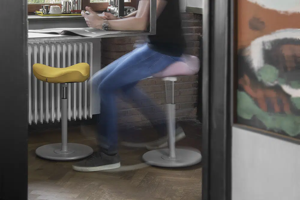 Varier Move sit-stand stool in yellow, in a home setting